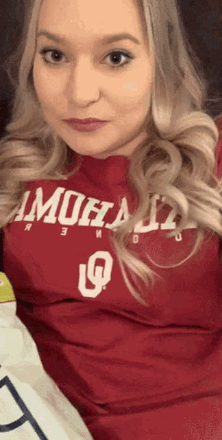 a woman wearing a red shirt that says ' oklahoma ' on the front