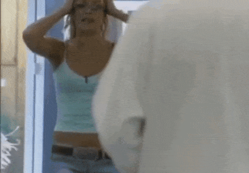 a woman is standing in front of a mirror looking at herself .