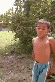 a shirtless young boy in blue shorts is standing in the grass
