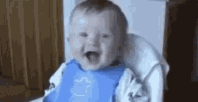 a baby is sitting in a high chair with his mouth open and smiling .