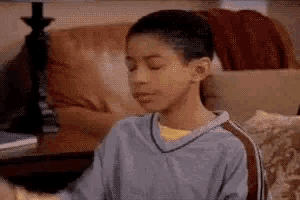 a young boy sitting on a couch with his eyes closed .