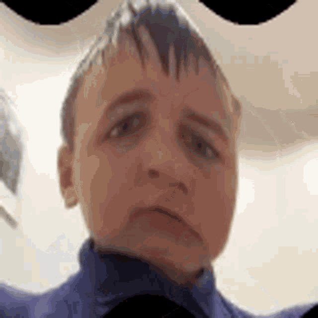 a young boy is making a sad face in front of a camera .