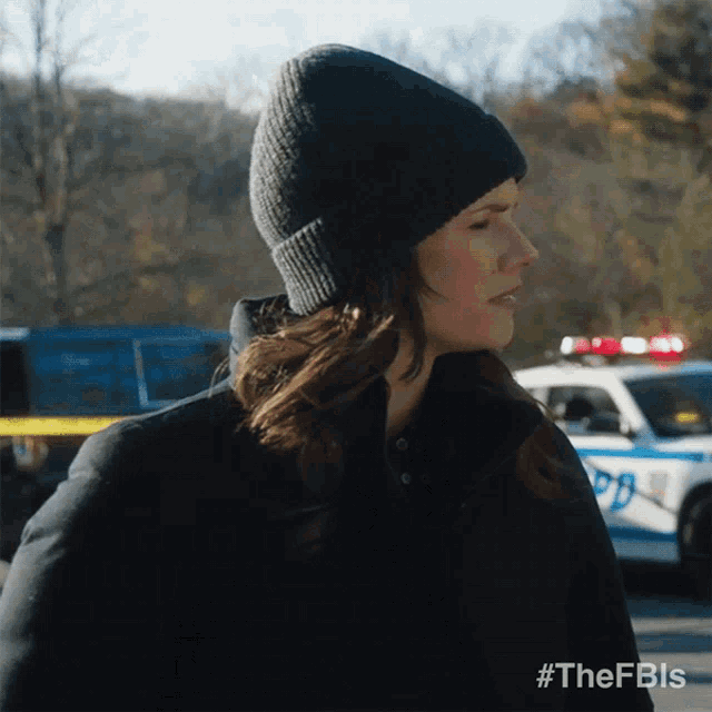 a woman wearing a beanie stands in front of a police car with the hashtag #thefbls