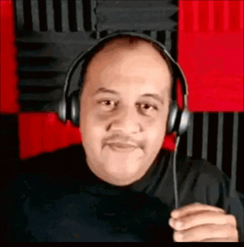 a man wearing headphones and a mustache is holding a microphone .