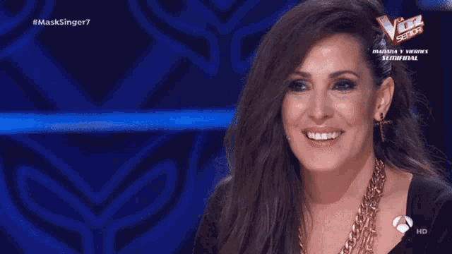 a woman is smiling in front of a blue background that says masksinger7