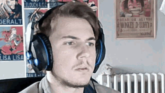 a man wearing a pair of headphones with a monkey d luffy poster in the background