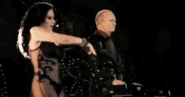 a woman in a black dress is dancing on a stage in front of a man .