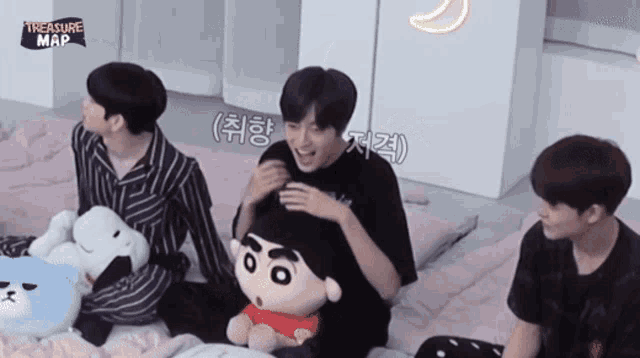 a group of young men are sitting on a bed with stuffed animals and a sign that says treasure map on it