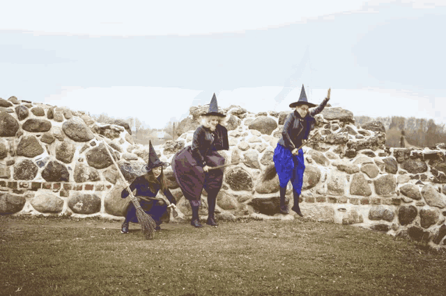 three witches are posing for a picture with their brooms in front of a stone wall