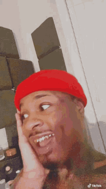 a man wearing a red hat is making a funny face with his tongue out .