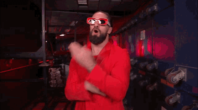 a man in a red suit and sunglasses is standing in a dark room