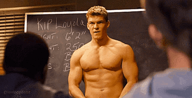 a shirtless man stands in front of a blackboard that says kip loyala on it