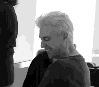 a black and white photo of a man with white hair laughing .
