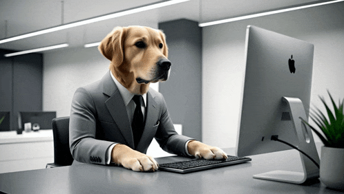 a dog wearing a suit and tie is sitting at a desk in front of an apple computer