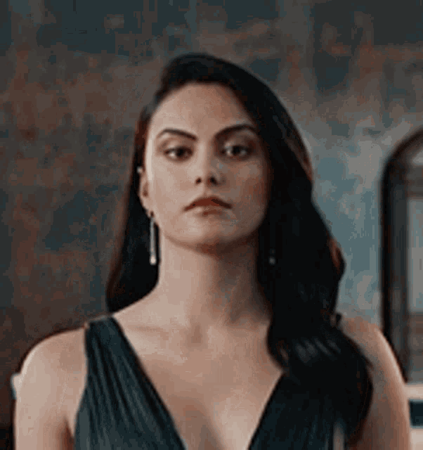 a woman in a black dress and earrings is standing in front of a mirror .