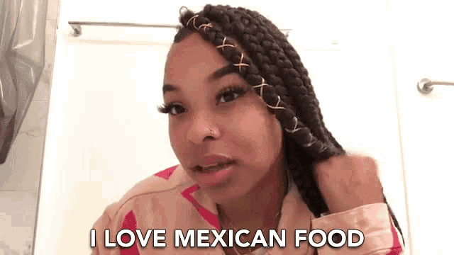 a woman with braids says " i love mexican food " in a bathroom