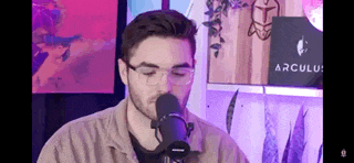 a man wearing glasses is singing into a microphone in a room .