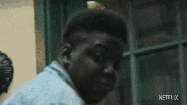 a man is standing in front of a green door and looking out the window .