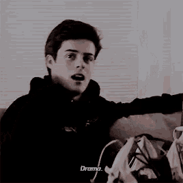 a young man is sitting on a couch with his mouth open and talking about drama .