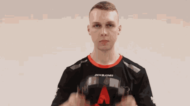 a young man wearing a jack jones shirt is holding a pair of headphones in his hands .