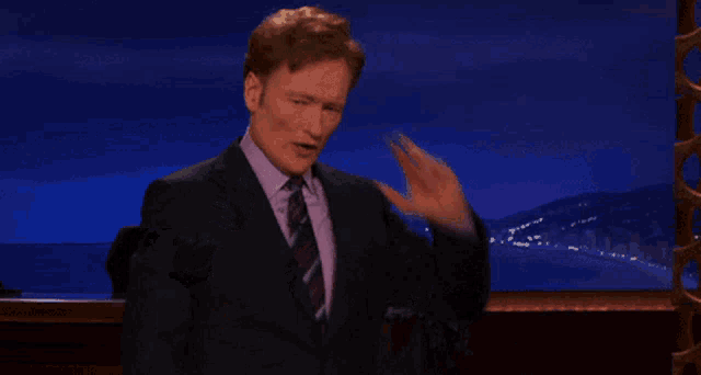 a man in a suit and tie is making a stop gesture