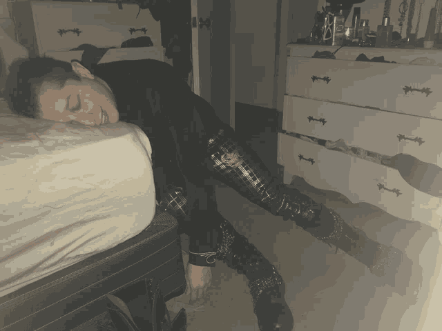a person laying on a bed next to a dresser with a few bottles of lotion on it