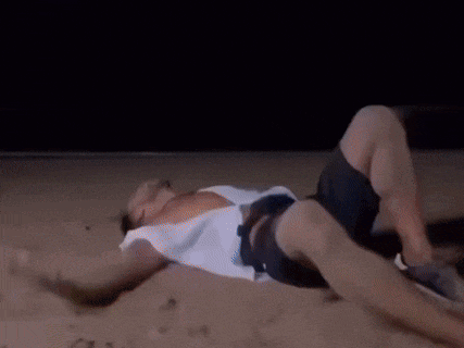a man is laying on his stomach on the beach .
