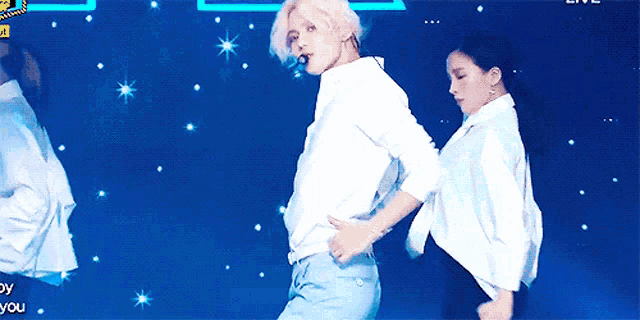 a man in a white shirt and blue pants is dancing on stage
