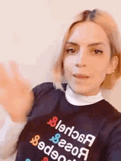 a woman wearing a black t-shirt with the word blender on it is waving her hand .