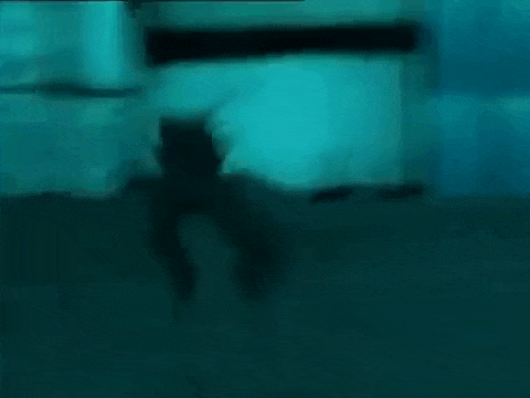 a blurry picture of a man kneeling down in front of a building in a dark room .