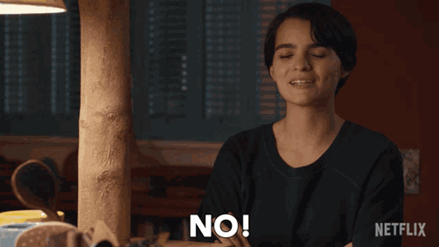 a woman is sitting at a table and says " no "