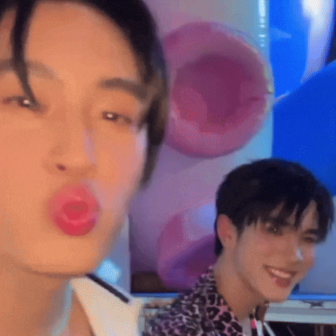 a close up of a person blowing a kiss with a pink balloon behind them .