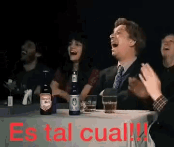 a group of people are sitting at a table with the words es tal cual written on the table