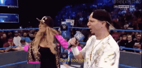 a man and a woman are in a wrestling ring and the woman is saying " don 't boo her "