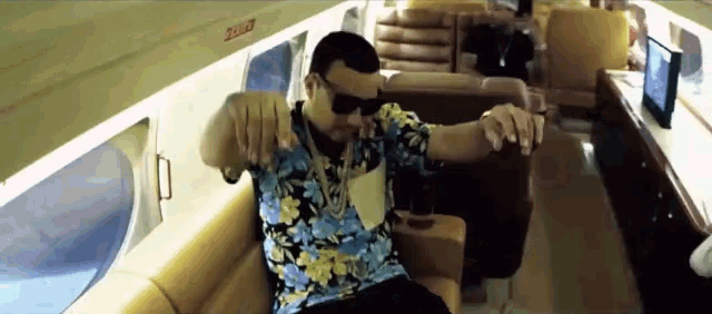 a man in a hawaiian shirt is sitting on a couch with a sign that says exit