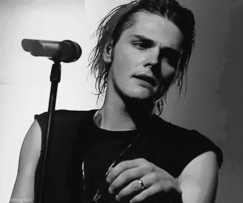 a black and white photo of a man singing into a microphone with a ring on his left hand