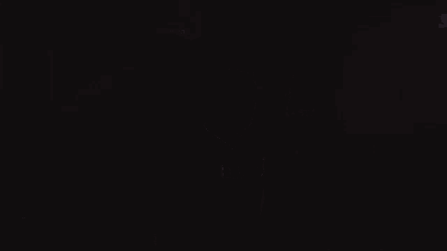 a man wearing a red hooded jacket is standing in the dark and looking at something .