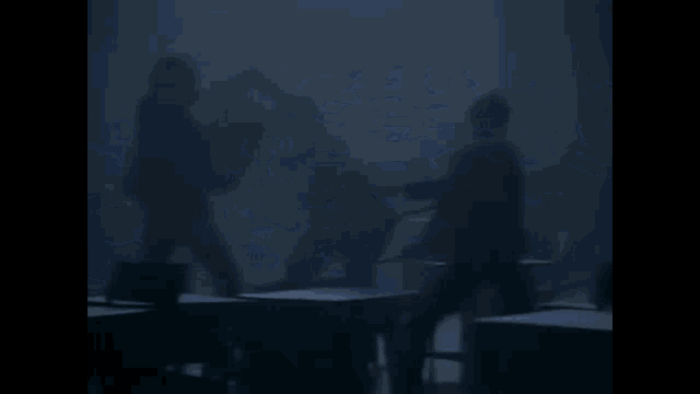 a silhouette of a person sitting at a desk in a dark room .