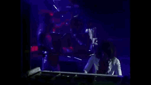 a woman is playing a piano on a stage in a dark room .