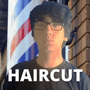 a man wearing glasses is standing in front of a barber shop sign that says haircut