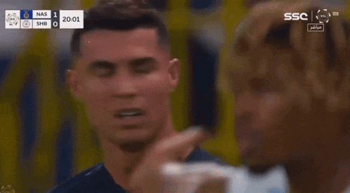 a man with a bandage on his face is talking to another man during a soccer match .