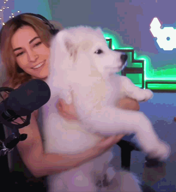 a woman is holding a white dog in her arms