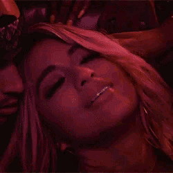 a man and a woman are laying on a bed . the woman is wearing braces on her teeth .