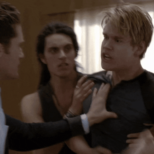 a man in a suit is holding another man 's arm while another man looks on