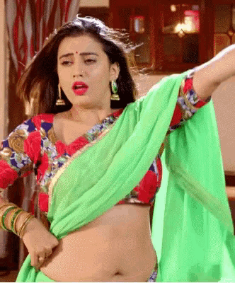 a woman in a green saree and a red blouse is dancing