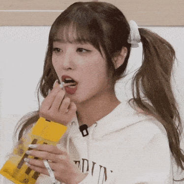 a girl in a ponytail is eating a snack from a bag