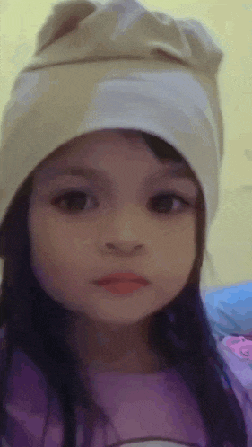 a little girl wearing a hat and a purple shirt