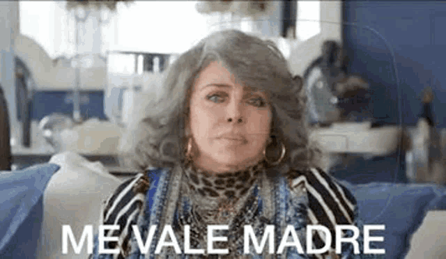 a woman is sitting on a couch with the words `` me vale madre '' written above her .