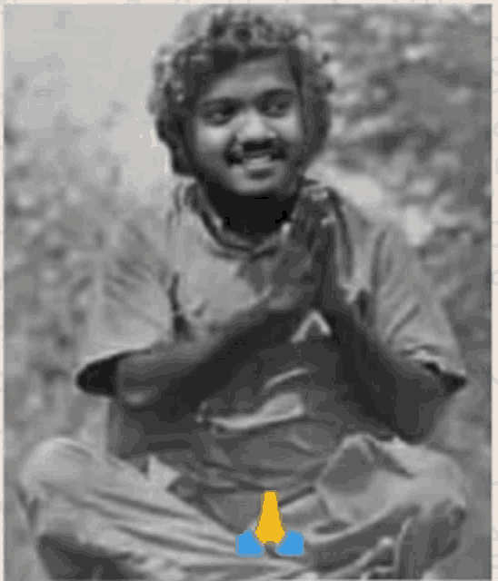 a black and white photo of a man sitting in a lotus position with his hands folded in prayer .