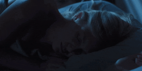 a woman is sleeping in a bed with a white pillow